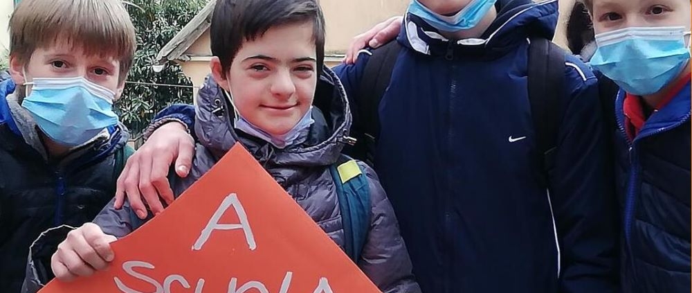 Alunni con un cartello con scritto "A scuola un posto per tutti c'è"