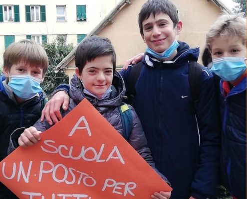 Alunni con un cartello con scritto "A scuola un posto per tutti c'è"